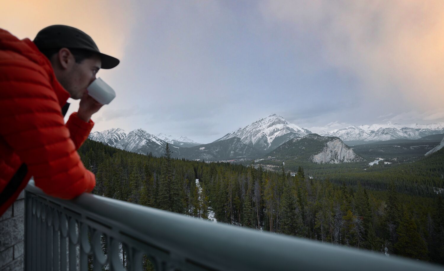 A person enjoys a coffee at the rimrock Resort Hotel in the early morning while looking at mountains.